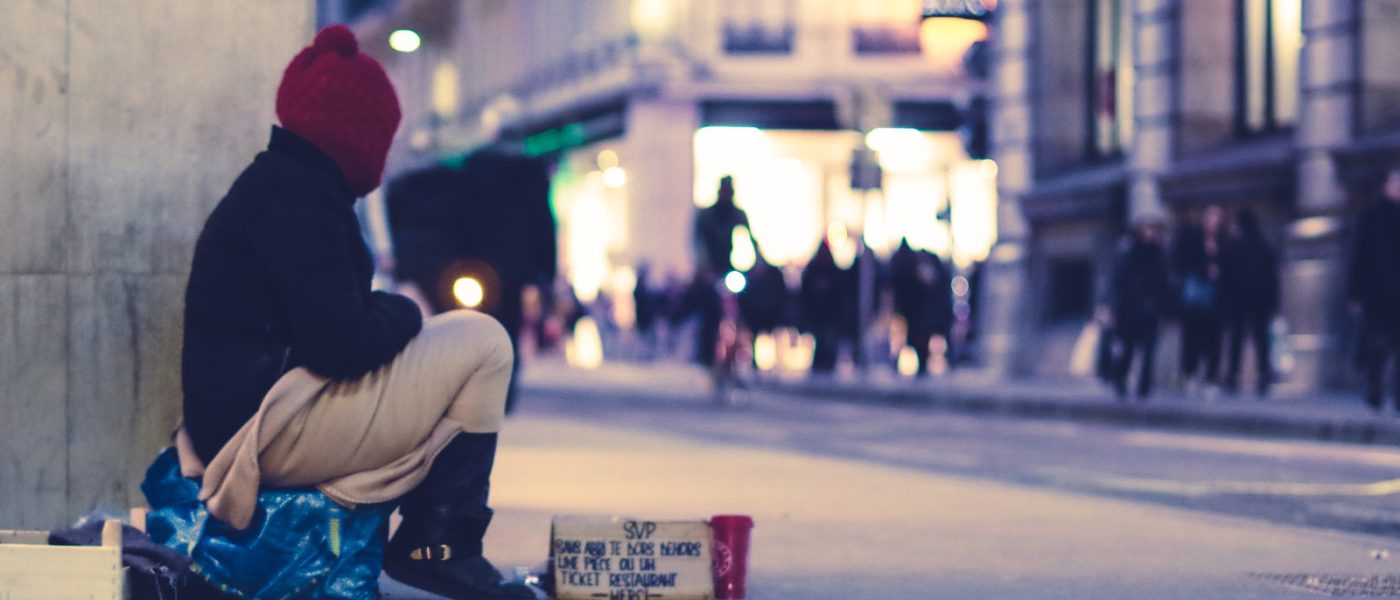 person sitting beside building looking straight to the street at golden hour